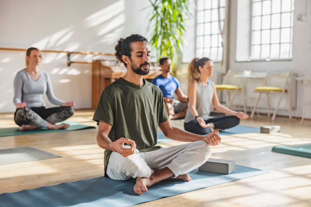 Person practicing yoga outdoors, highlighting exercise and stress management as key tips for living with Crohn’s disease.